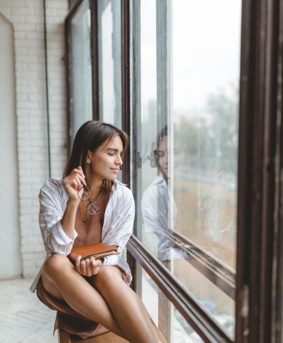 Just 10 minutes in nature reduces stress: how biophilia and biophilic design boost well‑being 2 woman looking out the window feeling good